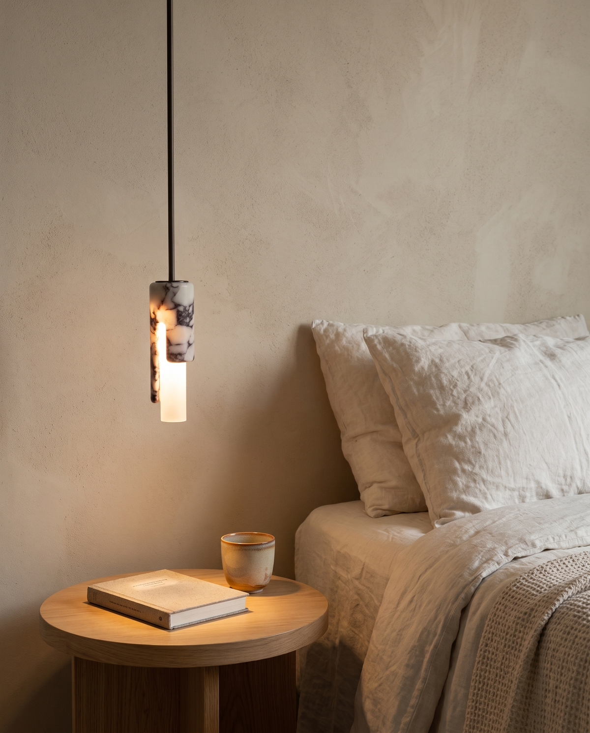 The Flute Pendant hung low beside a bed over an oak bedside table