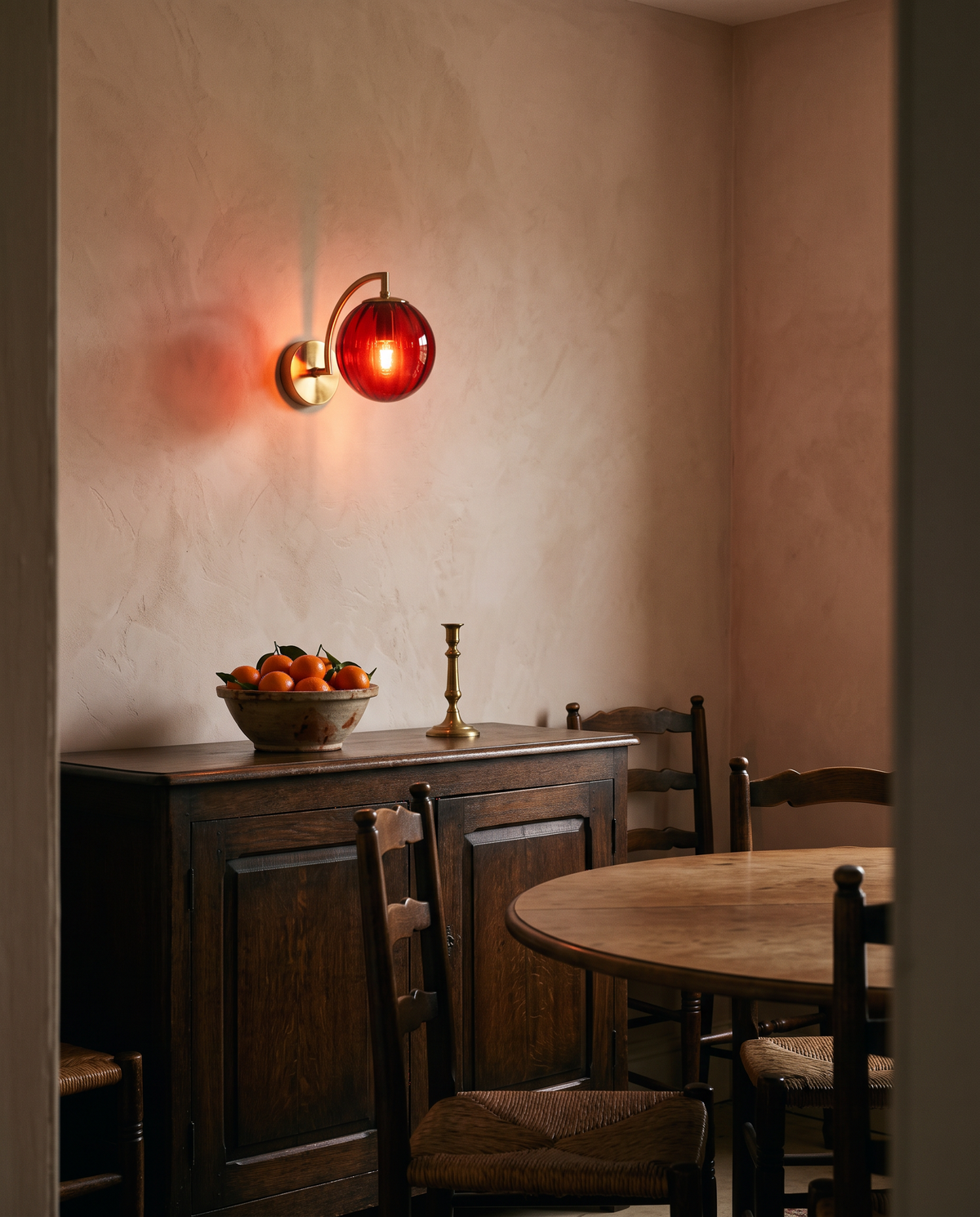 The Bloom wall sconce in red ribbed glass above an oak sideboard in a dining room