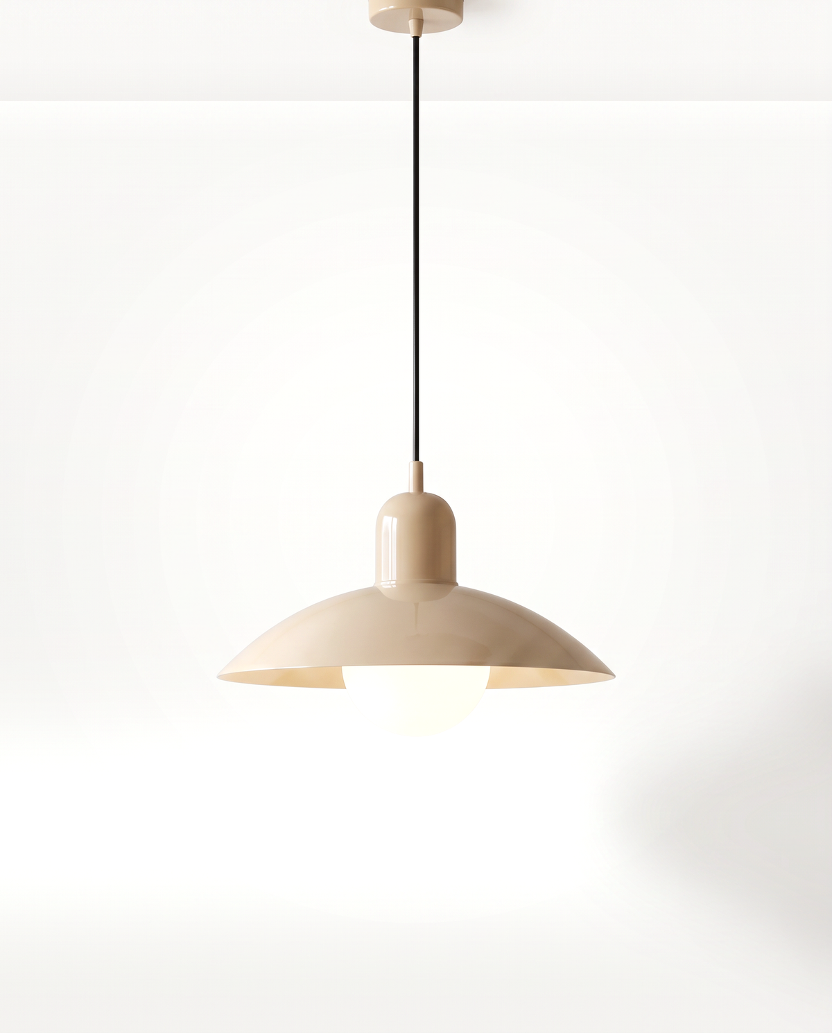 The Brolly Pendant in Sand, a wide lacquered metal disc over an opal globe bulb, lit