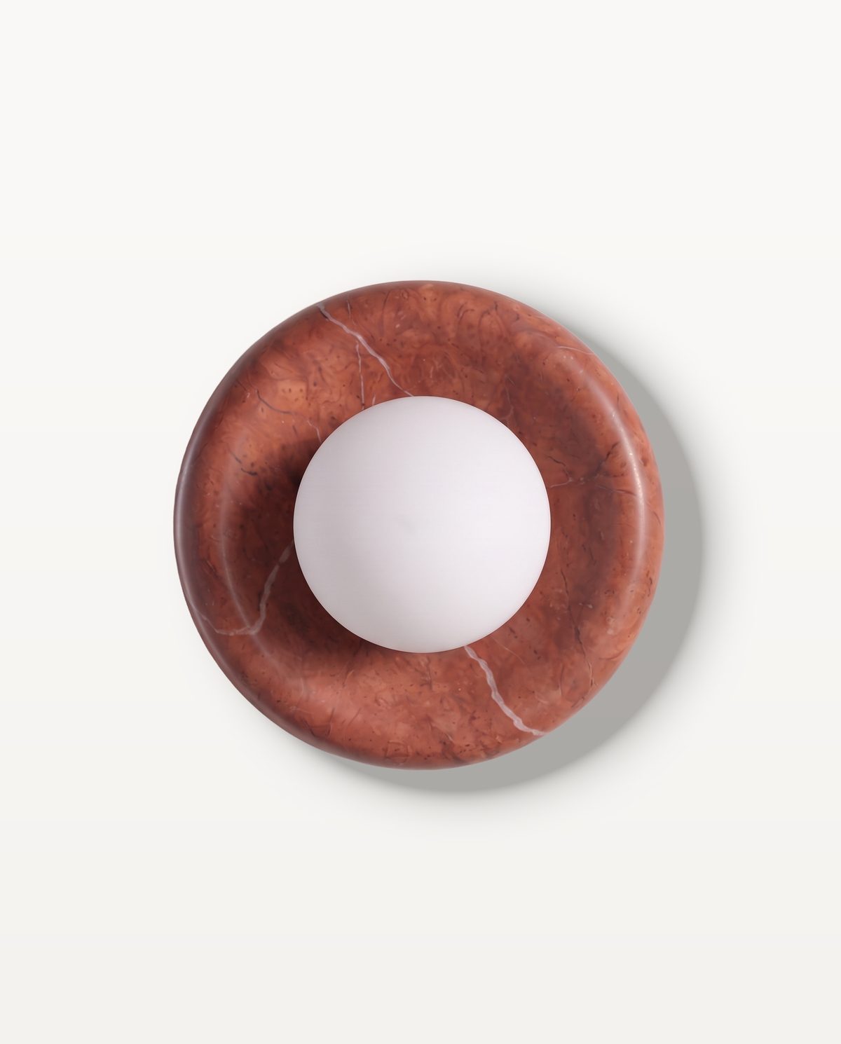 The Cameo Wall Light in Brick Red – a ring of brick red marble with a frosted glass globe, seen from the front