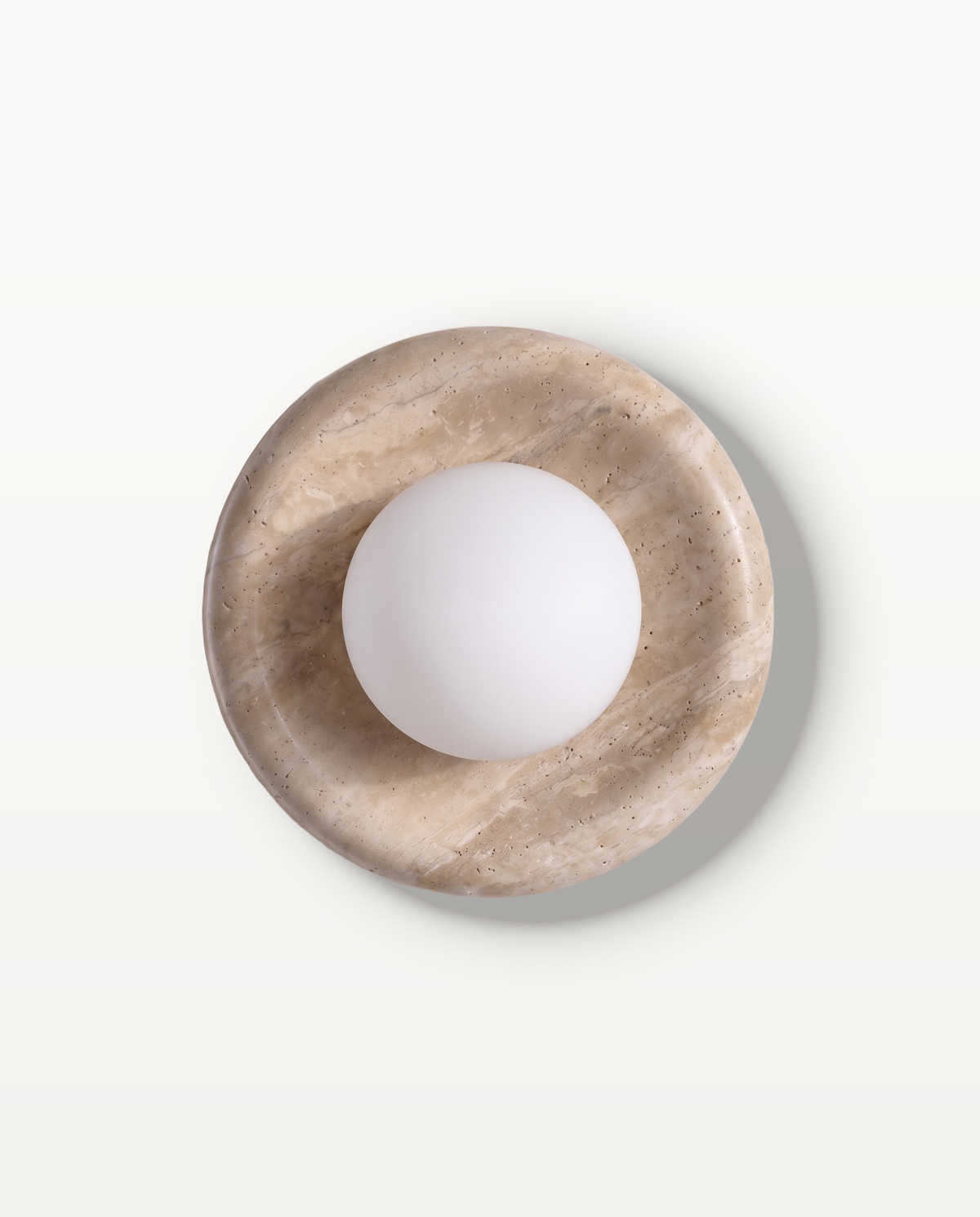 The Cameo Wall Light in Travertine – a ring of travertine with a frosted glass globe, seen from the front