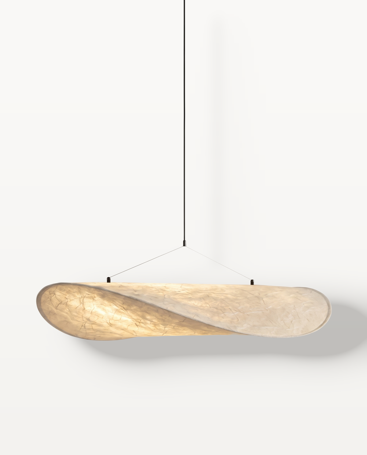 The Drift Pendant, a long shallow oval of creased paper with a twisted end, lit
