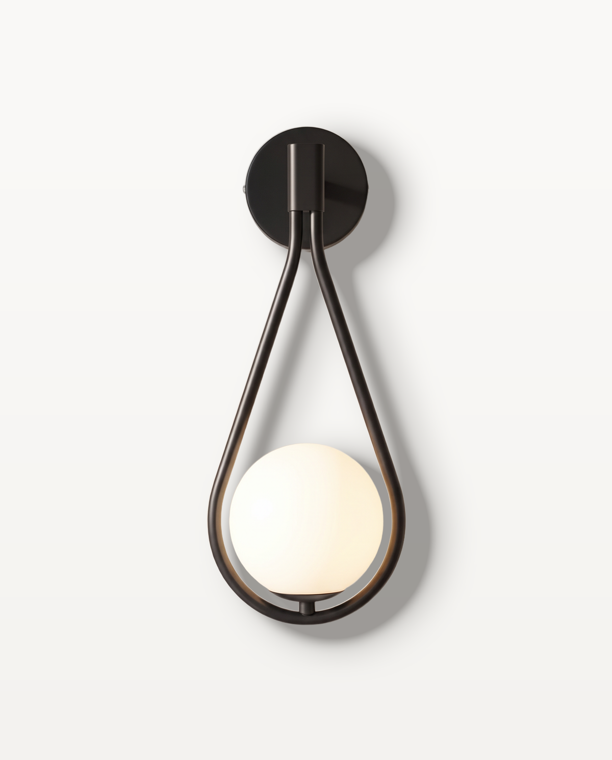 The Droplet Wall Light in matt black – a teardrop frame cradling an opal glass globe