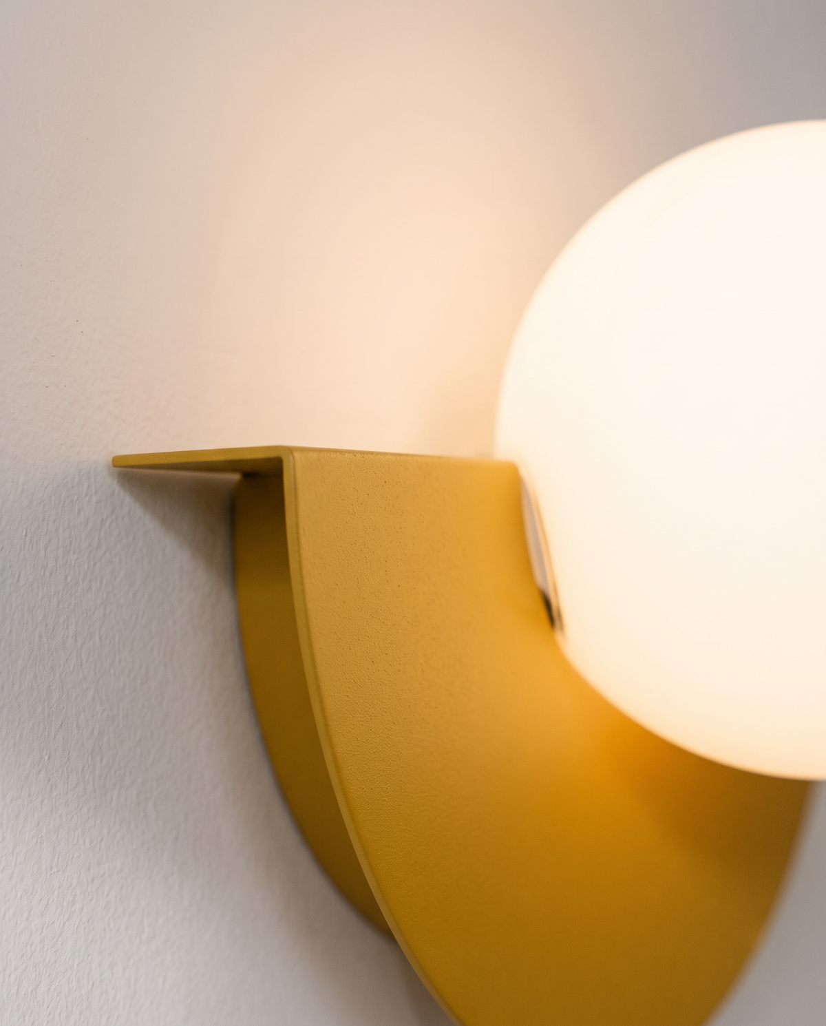 Close-up of the opal globe resting in the Mustard shade of The Fanlight