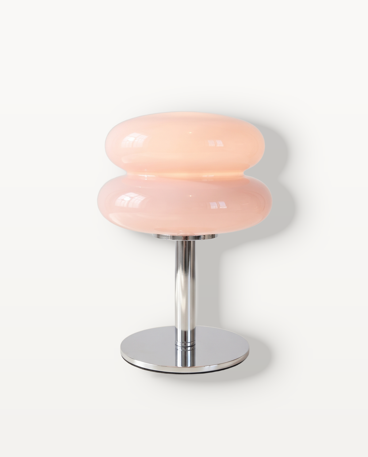 The Fondant Cordless Table Lamp in Blush, a glossy glass shade on a chrome stem, lit