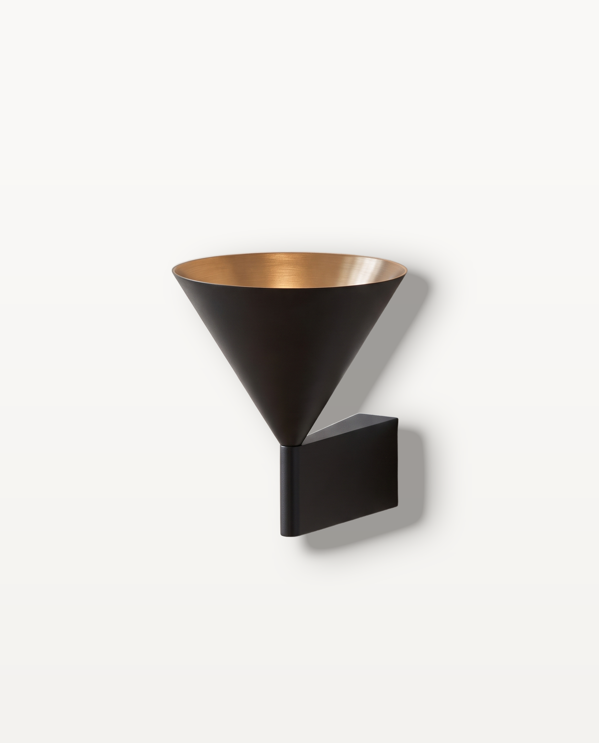 The Funnel, brushed aluminium cone wall light throwing a warm beam down the wall — Selden Home product photography