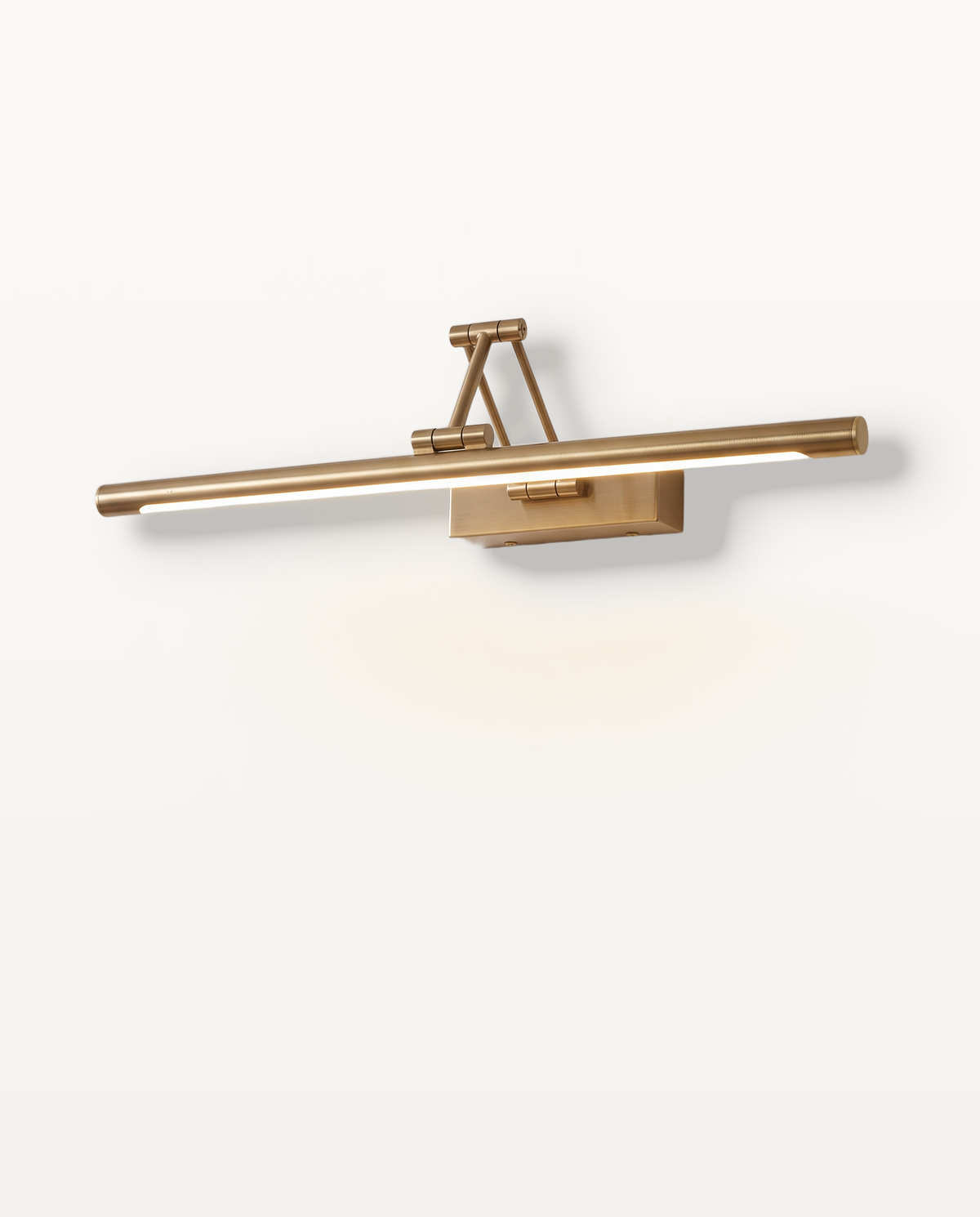 The Gallery Picture Light, a slim brushed brass bar on a hinged arm, lit