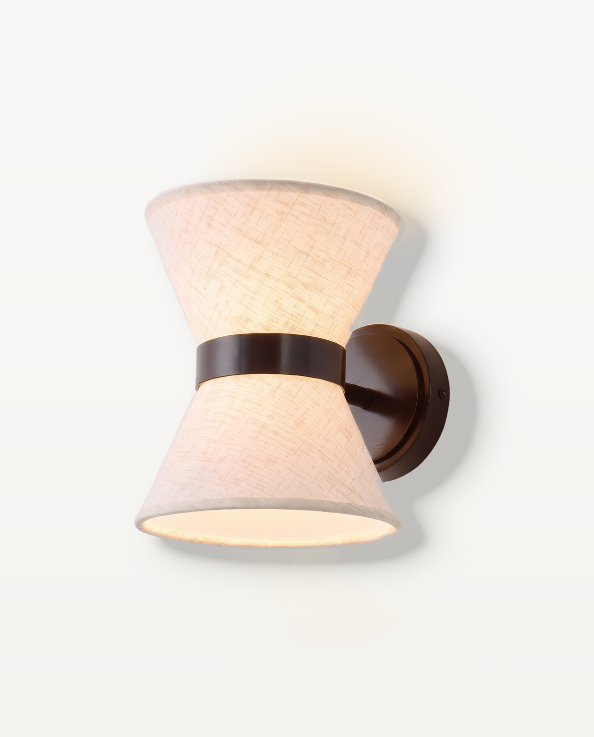 The Hourglass Wall Light, a cream fabric hourglass shade on a dark bronze arm, lit