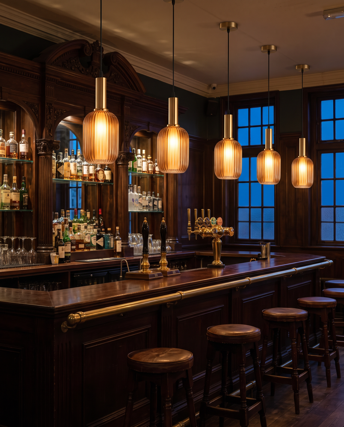 A row of amber Larder pendants over a traditional London pub bar