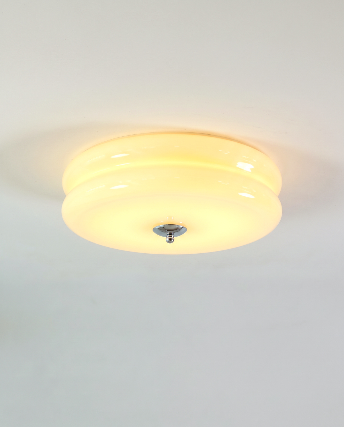 The Odeon Ceiling Light in Custard glass with a chrome finial, lit