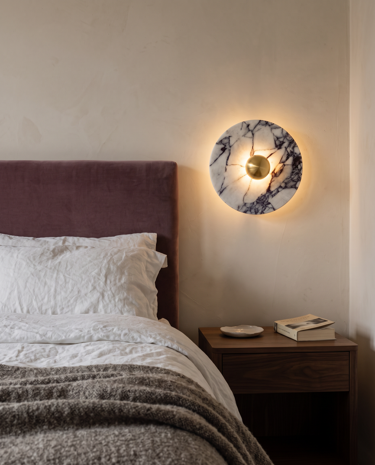 The Orb marble wall light in brass above a bedside table