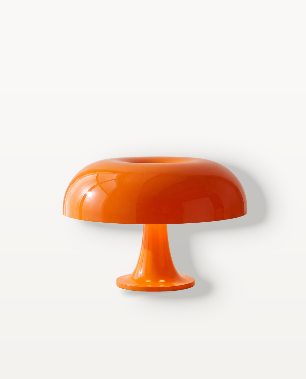 The Parasol Cordless Table Lamp, a gloss orange mushroom dome on a flared stem, lit, on a limestone ledge