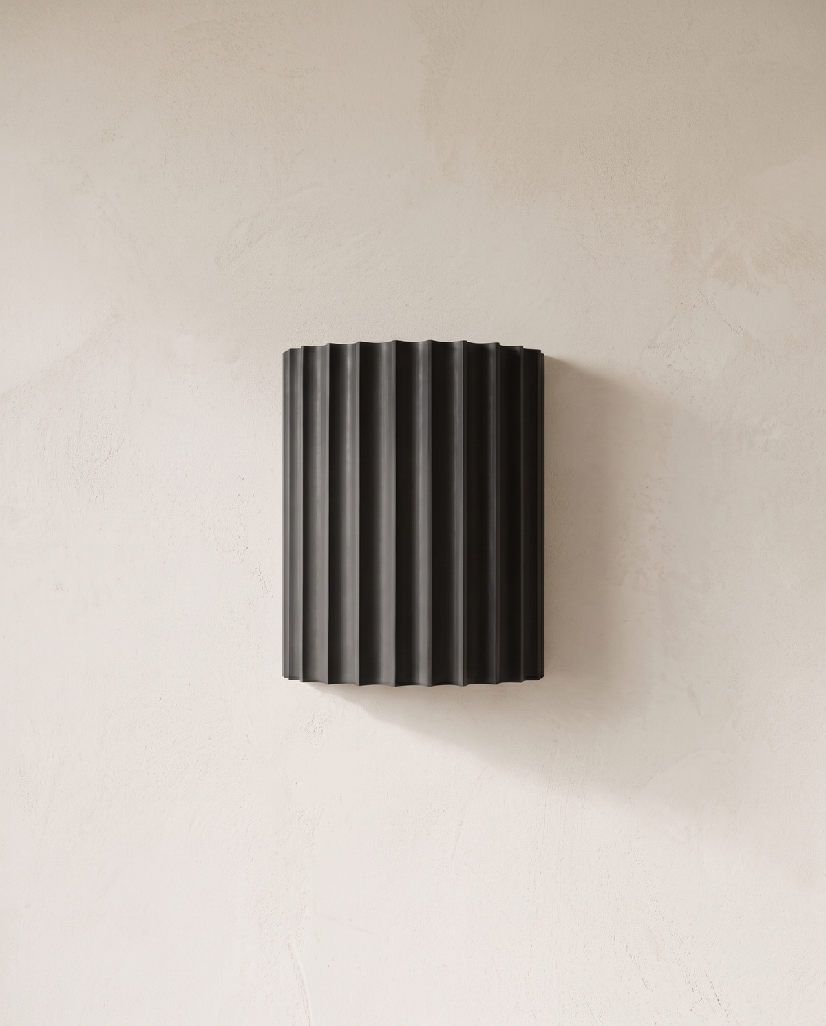 The Pleat, dark grey fluted wall light on lime-washed plaster wall — Selden Home product photography