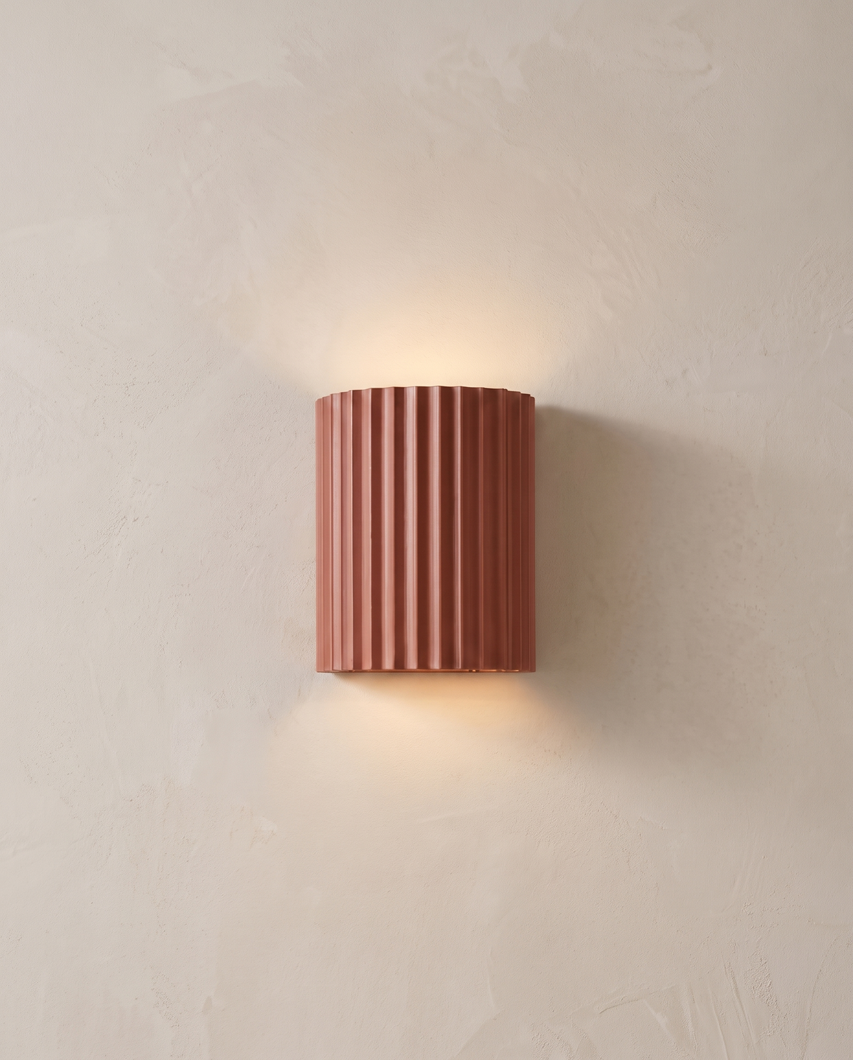 The Pleat, terracotta fluted wall light in situ on lime-washed plaster wall — Selden Home product photography