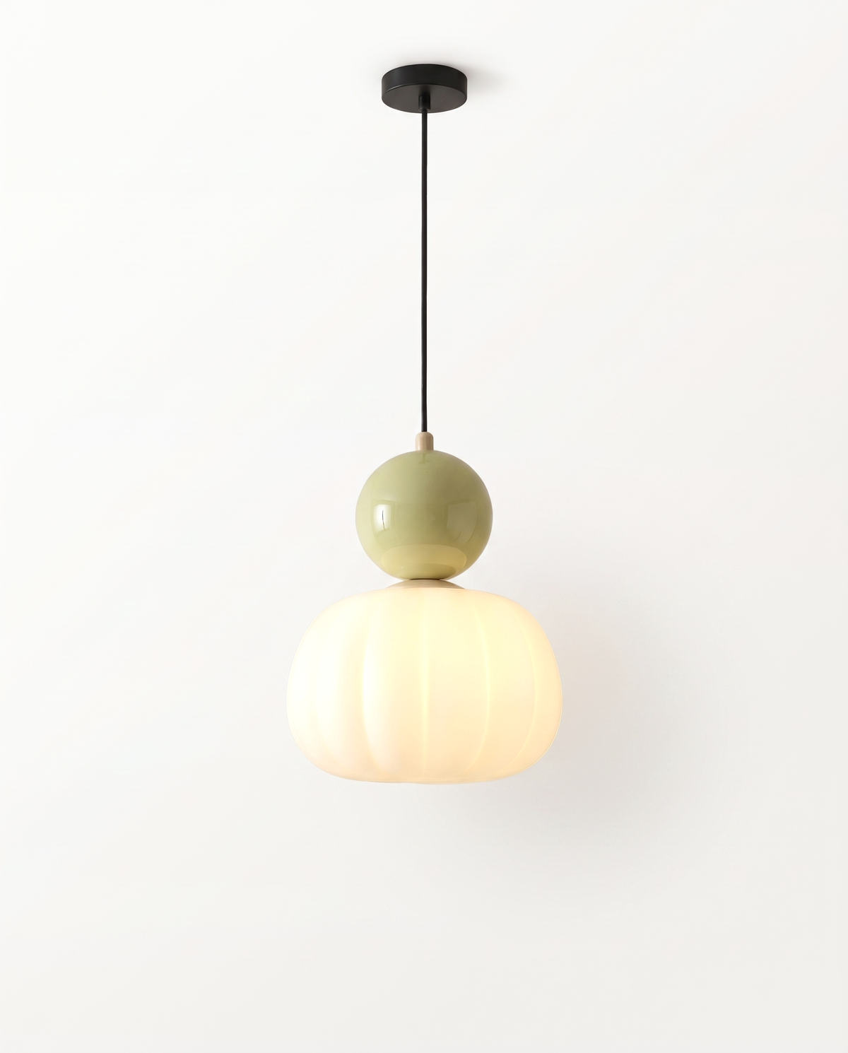 The Pomander Pendant with a pistachio ball over a fluted opal shade, lit