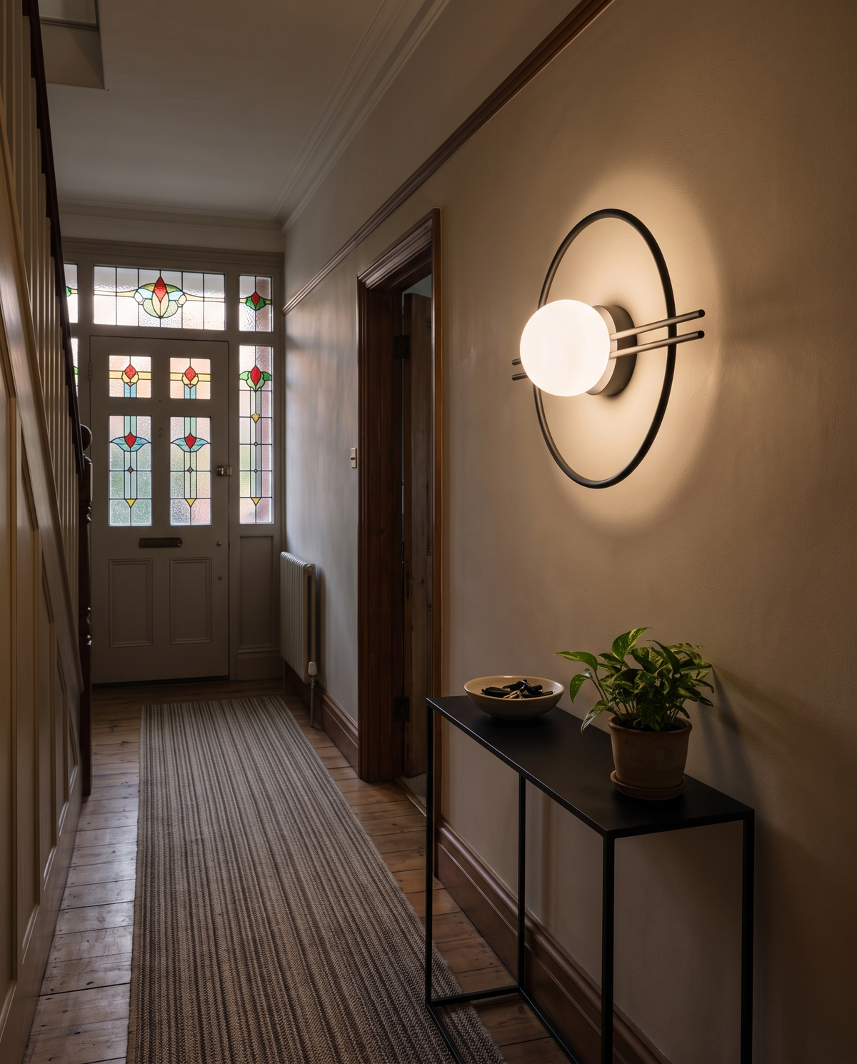 The Ring globe wall sconce in black in a 1930s hallway