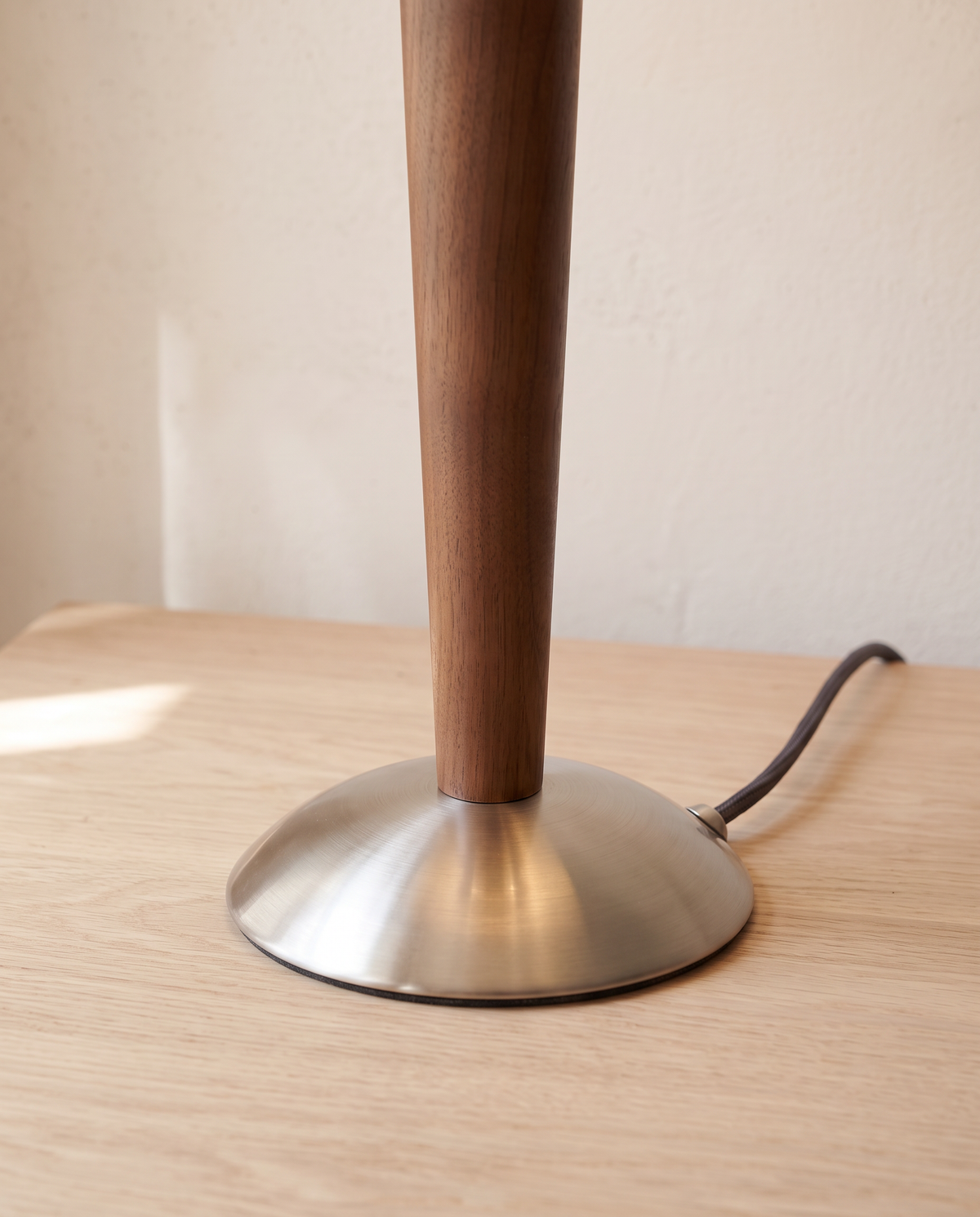 Close-up of the walnut stem and brushed nickel base of The Spindle