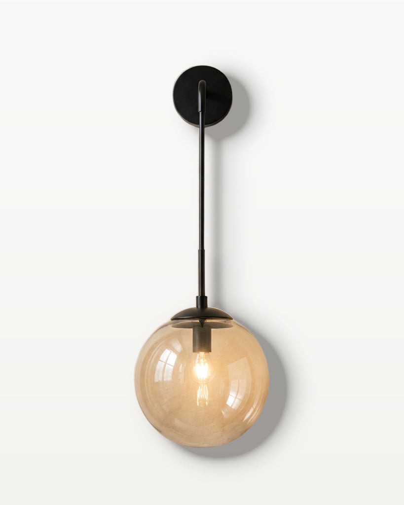 The Lantern, amber glass wall sconce on black hook arm, mounted on plaster wall — Selden Home product photography