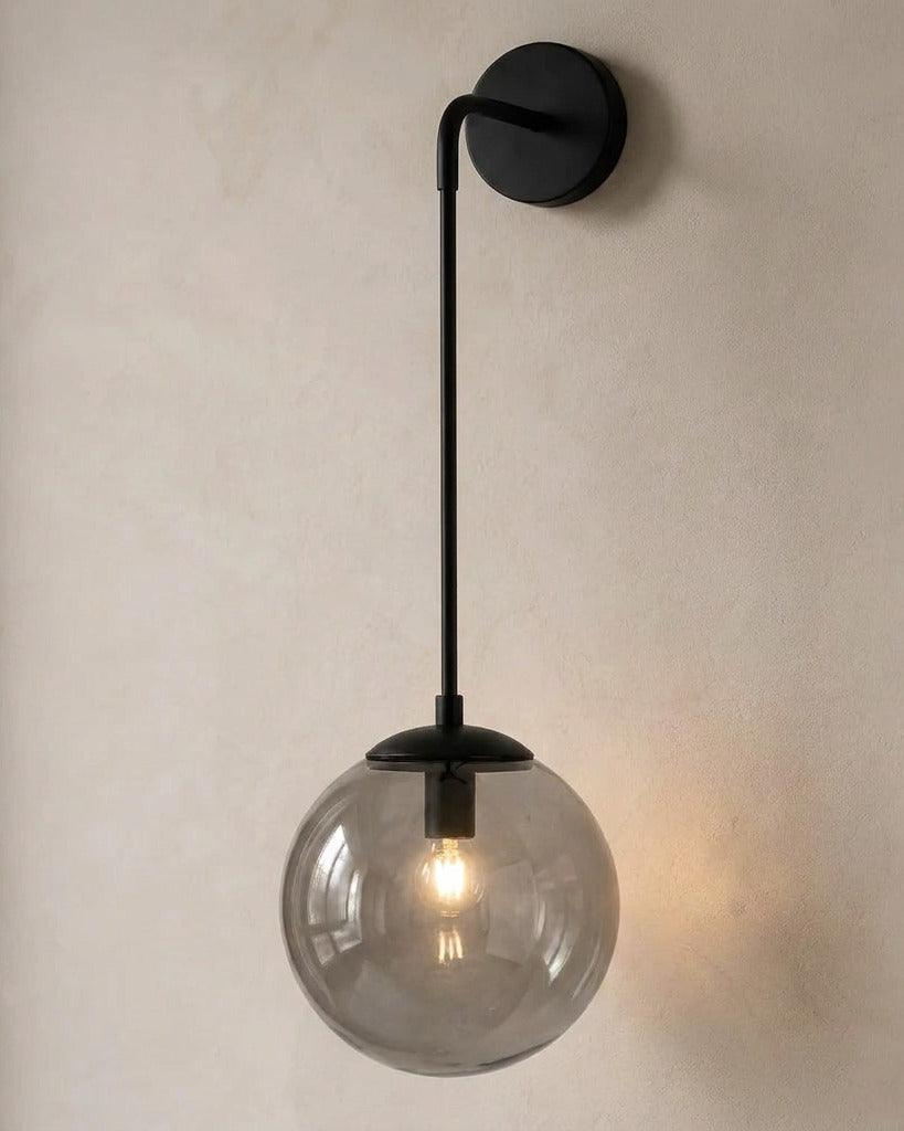The Lantern, smoke grey glass wall sconce on black hook arm, mounted on plaster wall — Selden Home product photography
