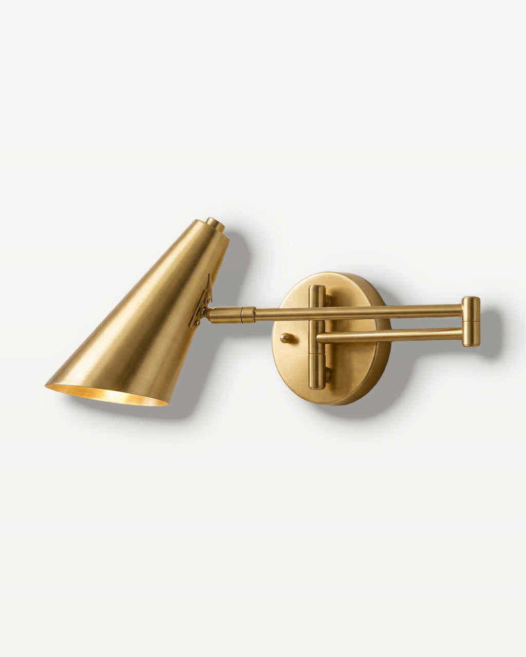 The Pivot, gold industrial swing arm wall light with cone shade, mounted on plaster wall — Selden Home product photography