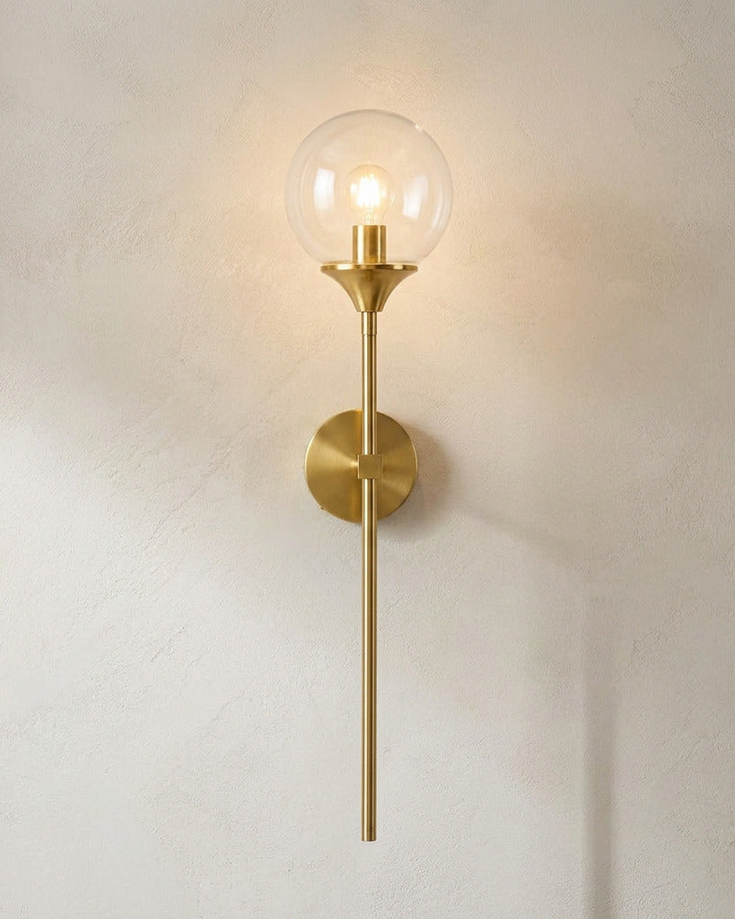 The Reed, gold long-stem wall sconce with clear glass globe, mounted on plaster wall — Selden Home product photography