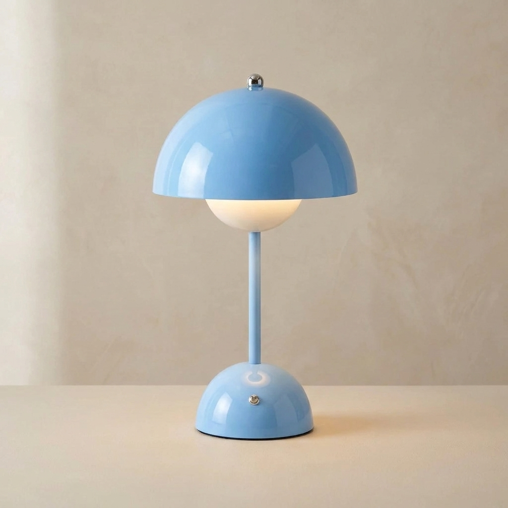 The Nomad blue cordless mushroom table lamp, lit, standing on a surface in front of a lime-washed plaster wall — Selden Home product photography