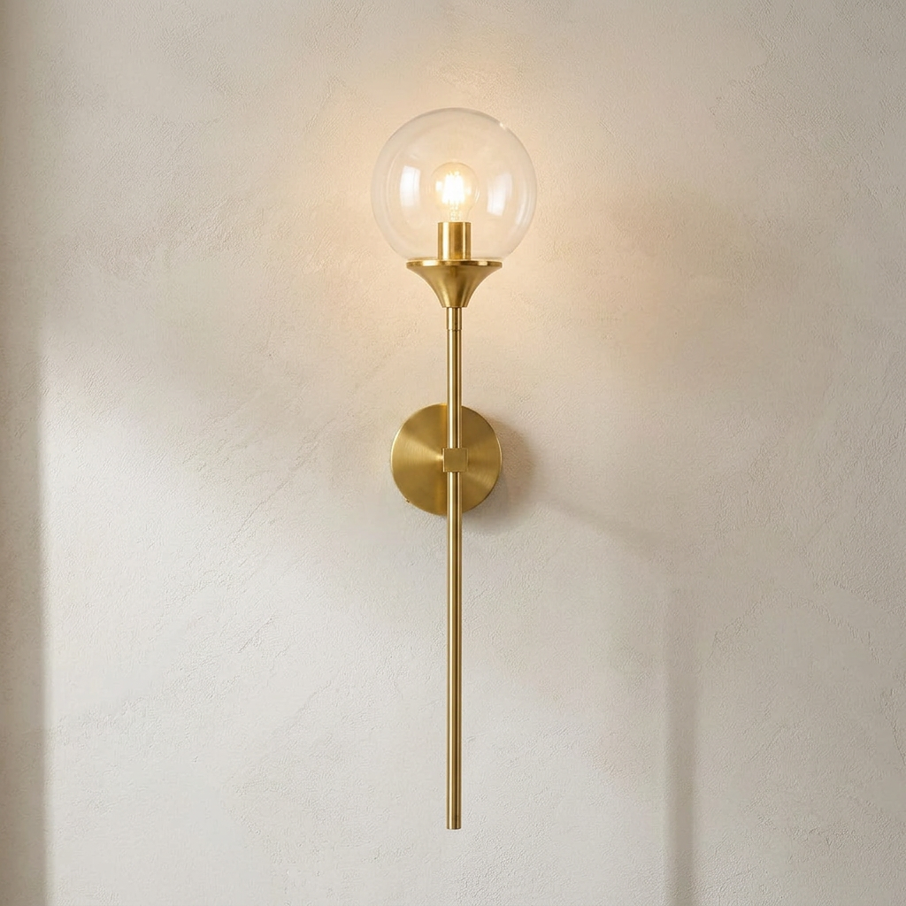 The Reed, gold long-stem wall sconce with clear glass globe, mounted on plaster wall — Selden Home product photography