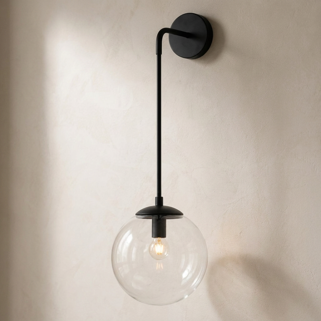 The Lantern, clear glass wall sconce on black hook arm, mounted on plaster wall — Selden Home product photography