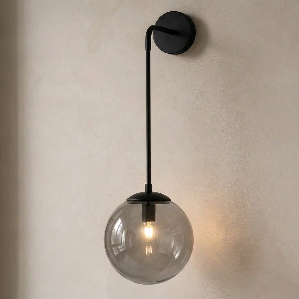 The Lantern, smoke grey glass wall sconce on black hook arm, mounted on plaster wall — Selden Home product photography