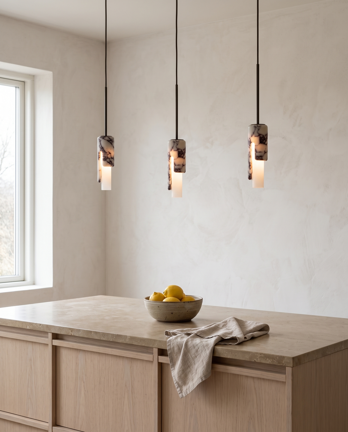 Three Flute marble pendants in a row over a kitchen island