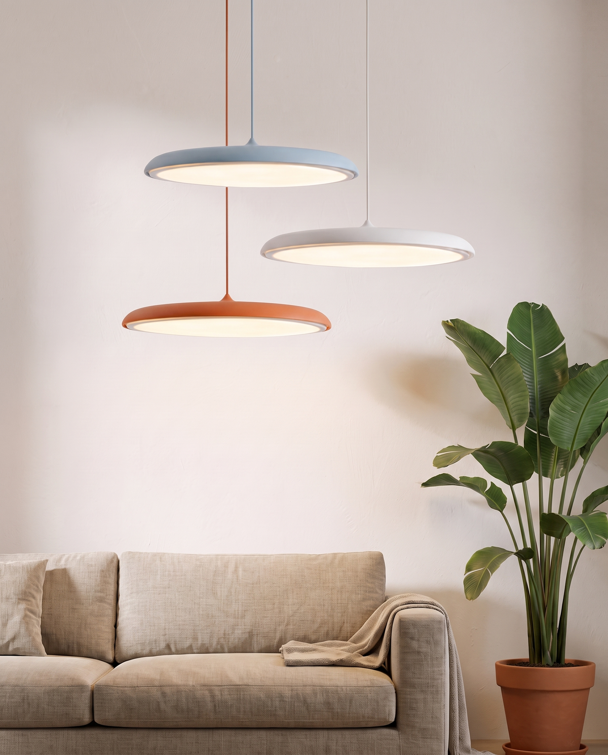 Three small Wafer pendants in blue, white and orange in a living room corner