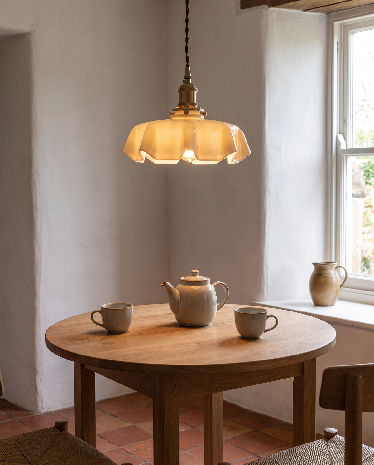 The Scallop Pendant in beige over a breakfast table by a window