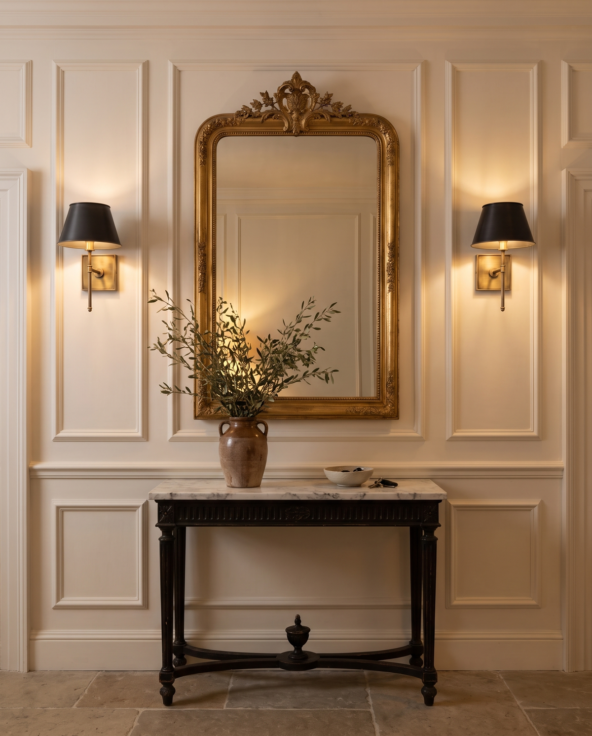 A pair of Bureau wall lights either side of a gilt mirror in a hallway