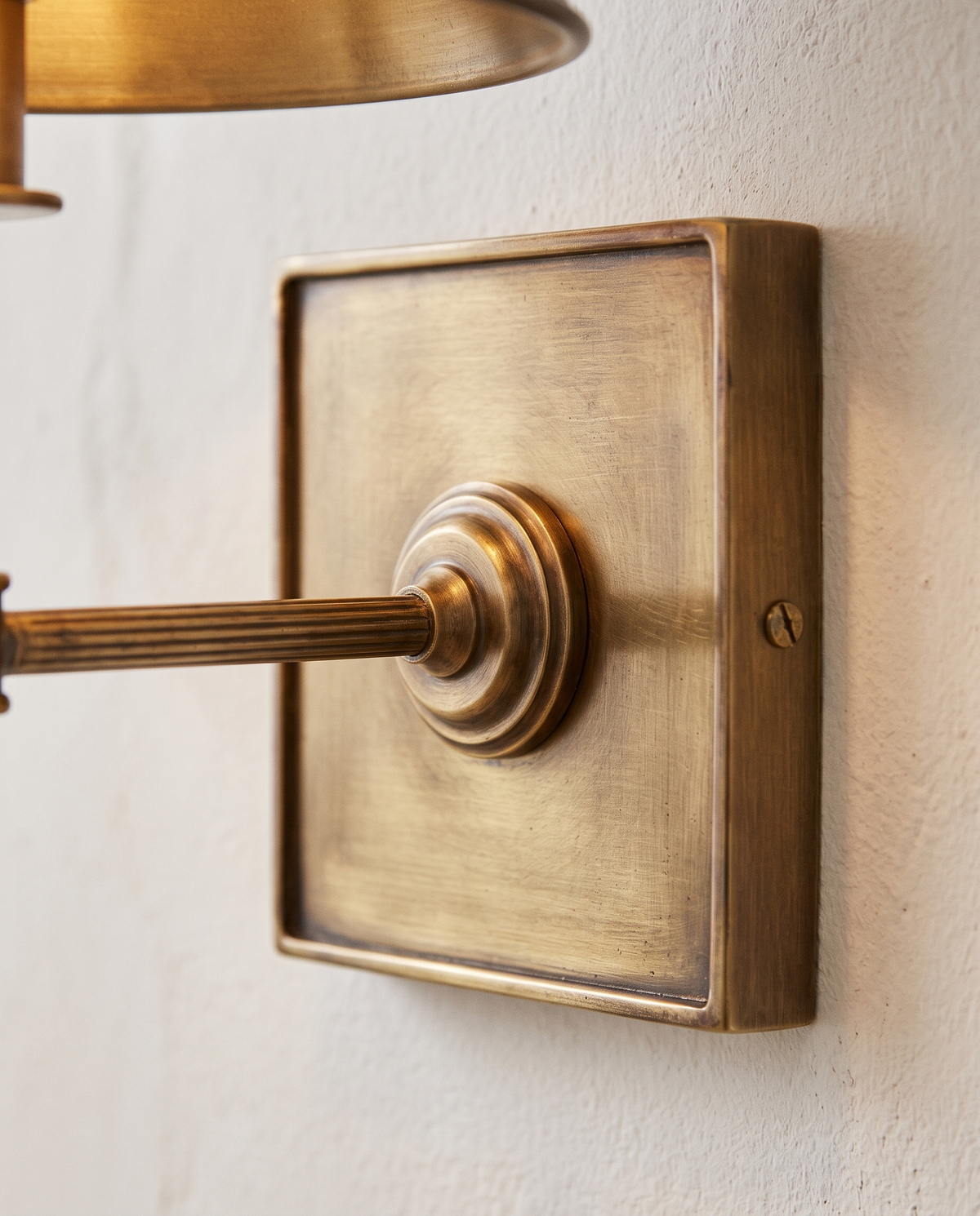 Close-up of the square antiqued brass wall plate of The Bureau