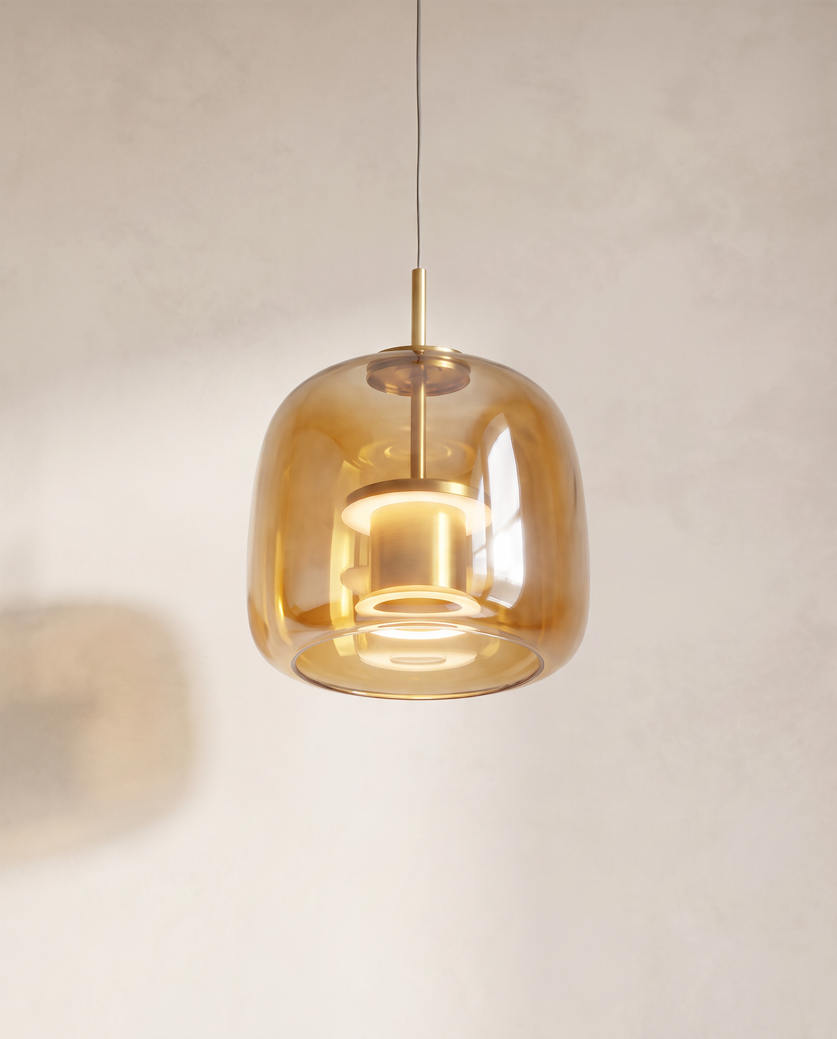 The Capsule Pendant in amber glass, lit