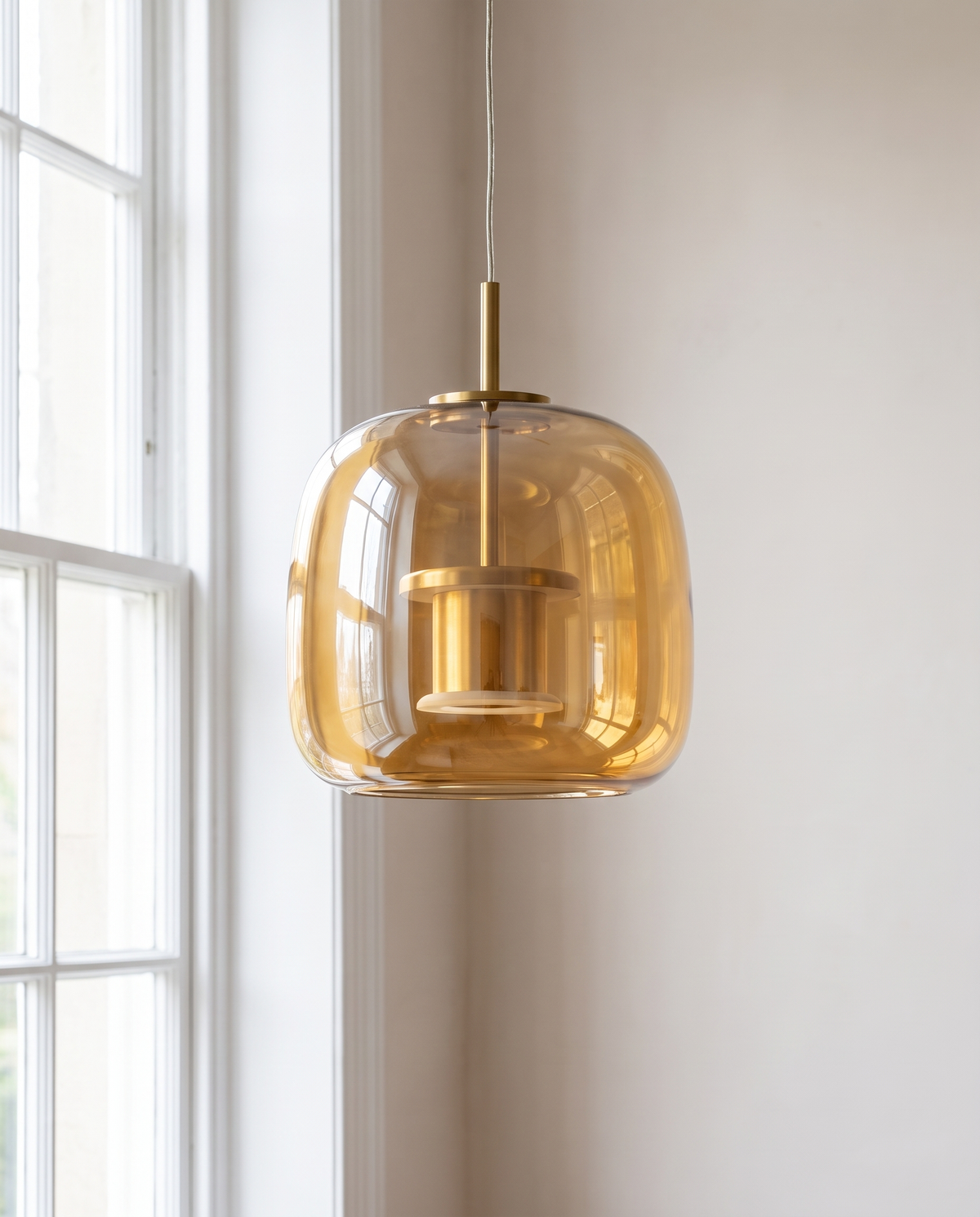 The amber Capsule Pendant in daylight beside a sash window