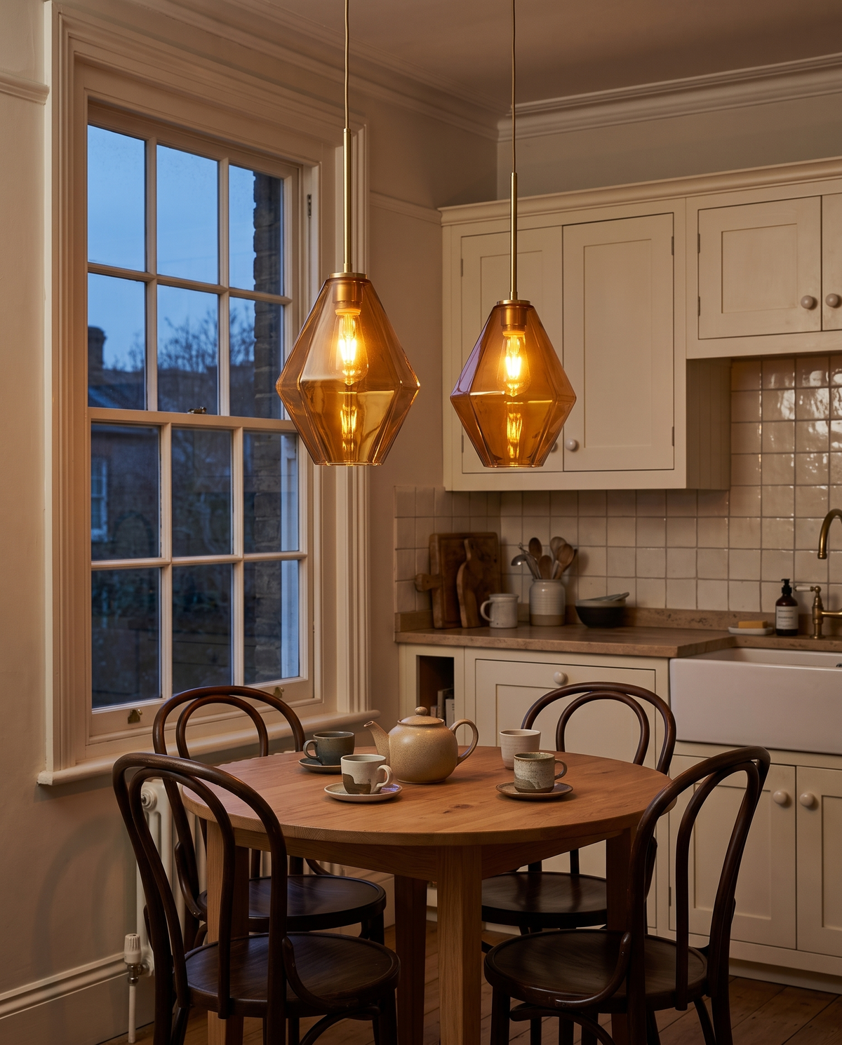 Two amber Carafe pendants over a round breakfast table in a Victorian kitchen