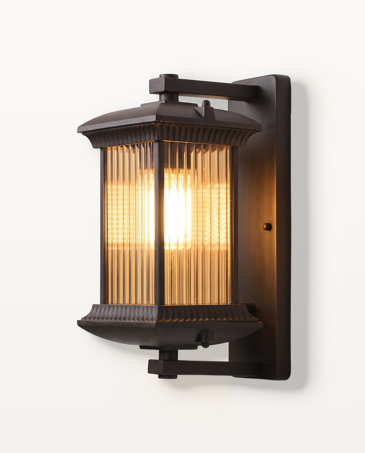The Coachman Outdoor Wall Light, a dark bronze lantern with fluted glass, lit