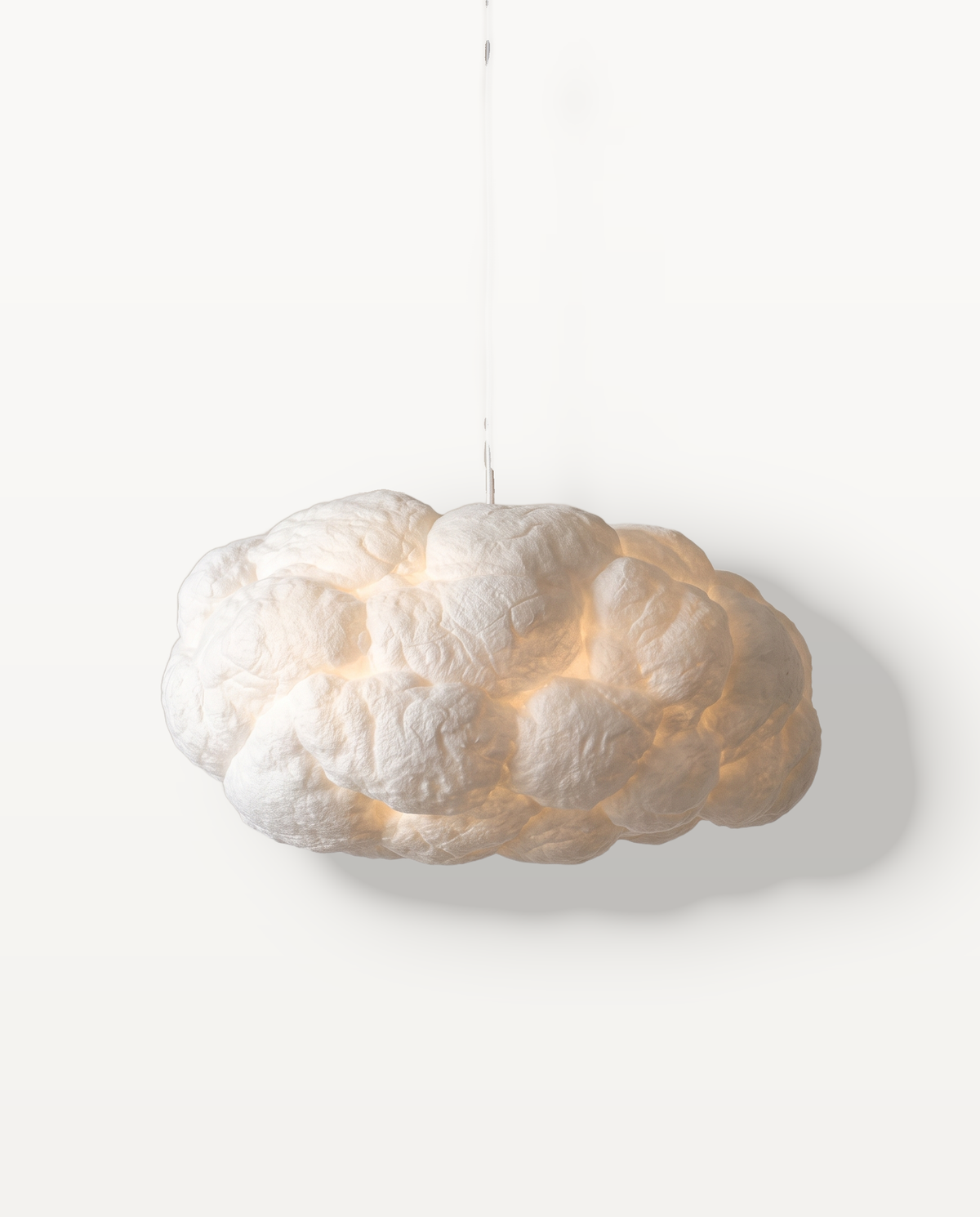 The Cumulus Pendant, a soft white cloud of textured fibre, lit