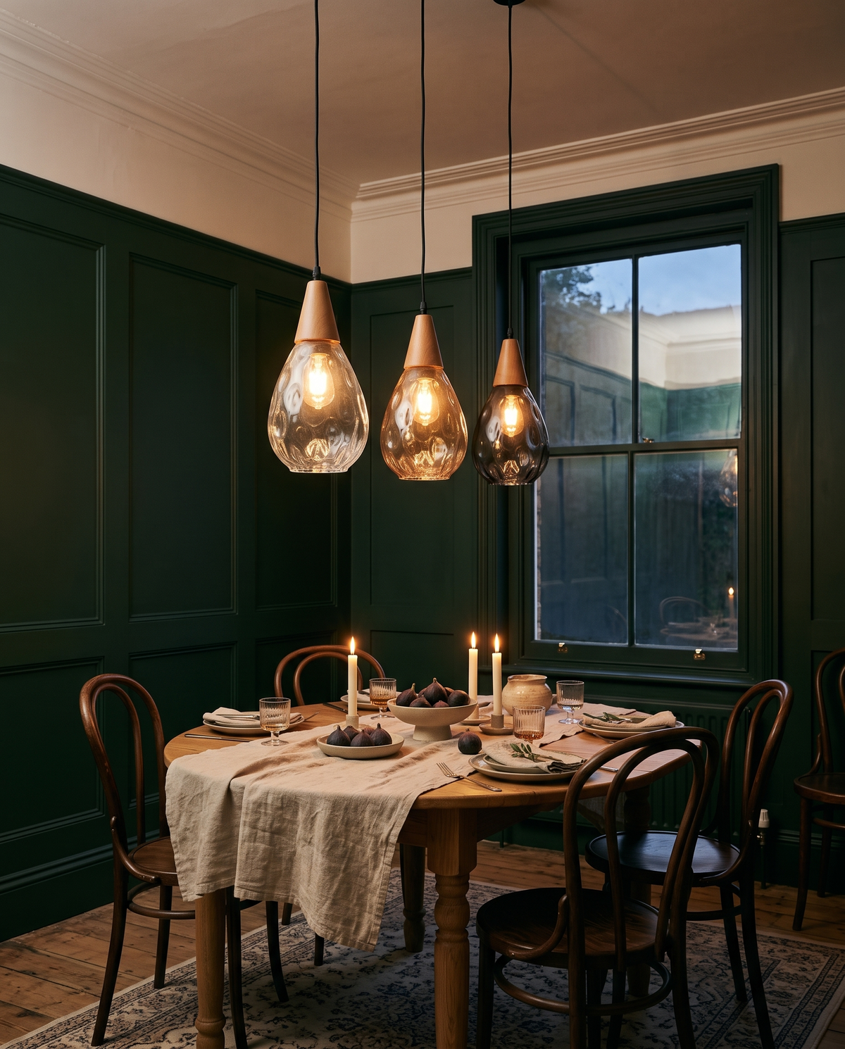 Three Dew pendants in clear, amber and smoke over a dining table