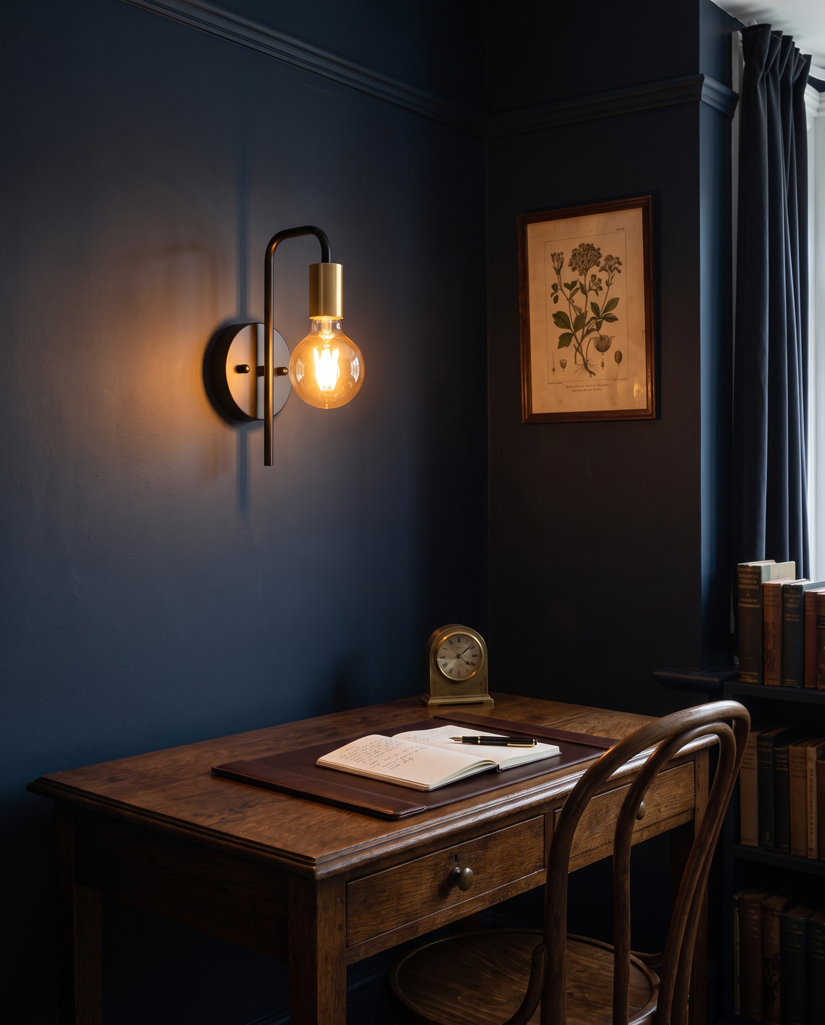 The Filament wall sconce in black and brass above a writing desk in a navy study