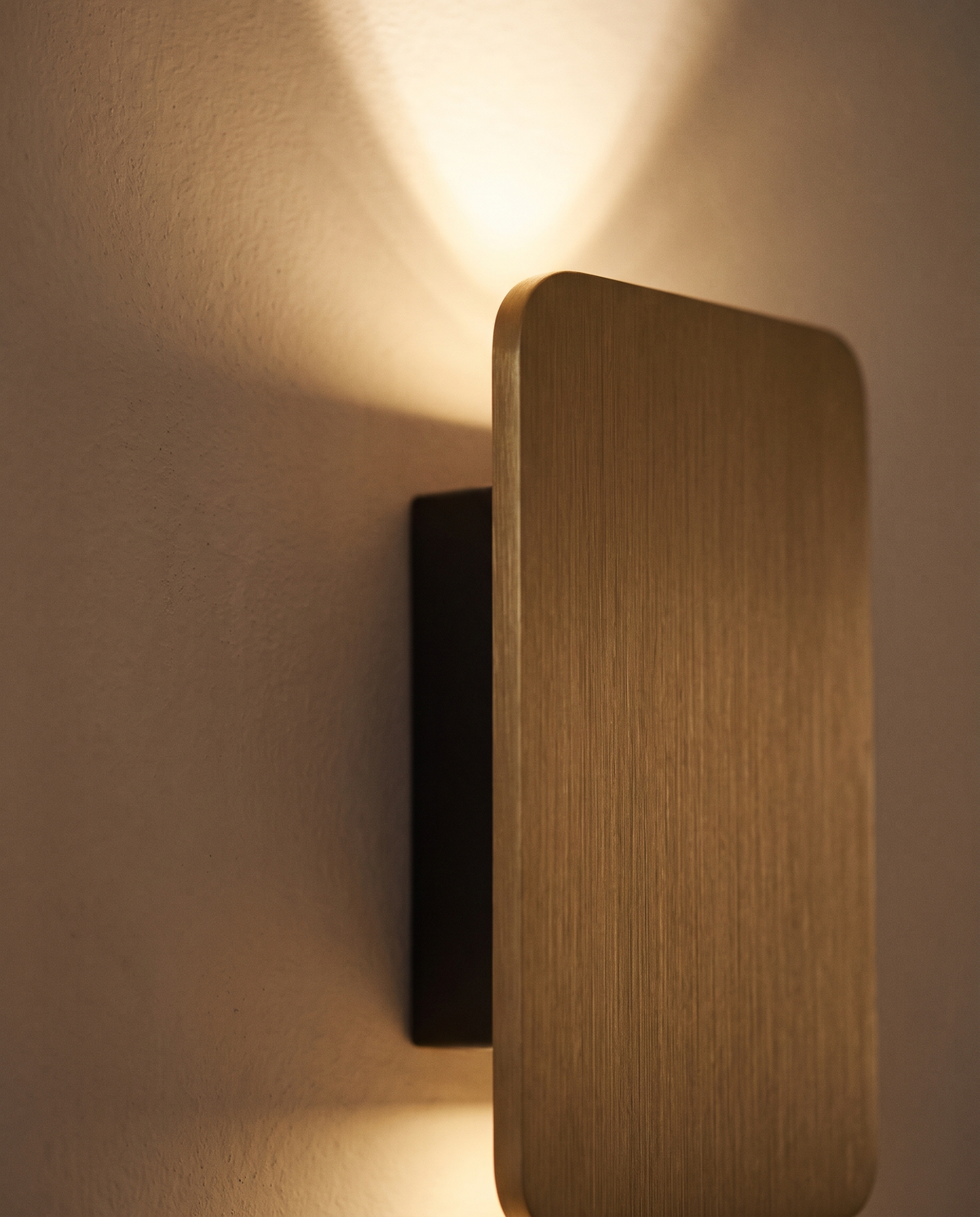 Close-up of the brushed metal plate of The Folio and its fan of light