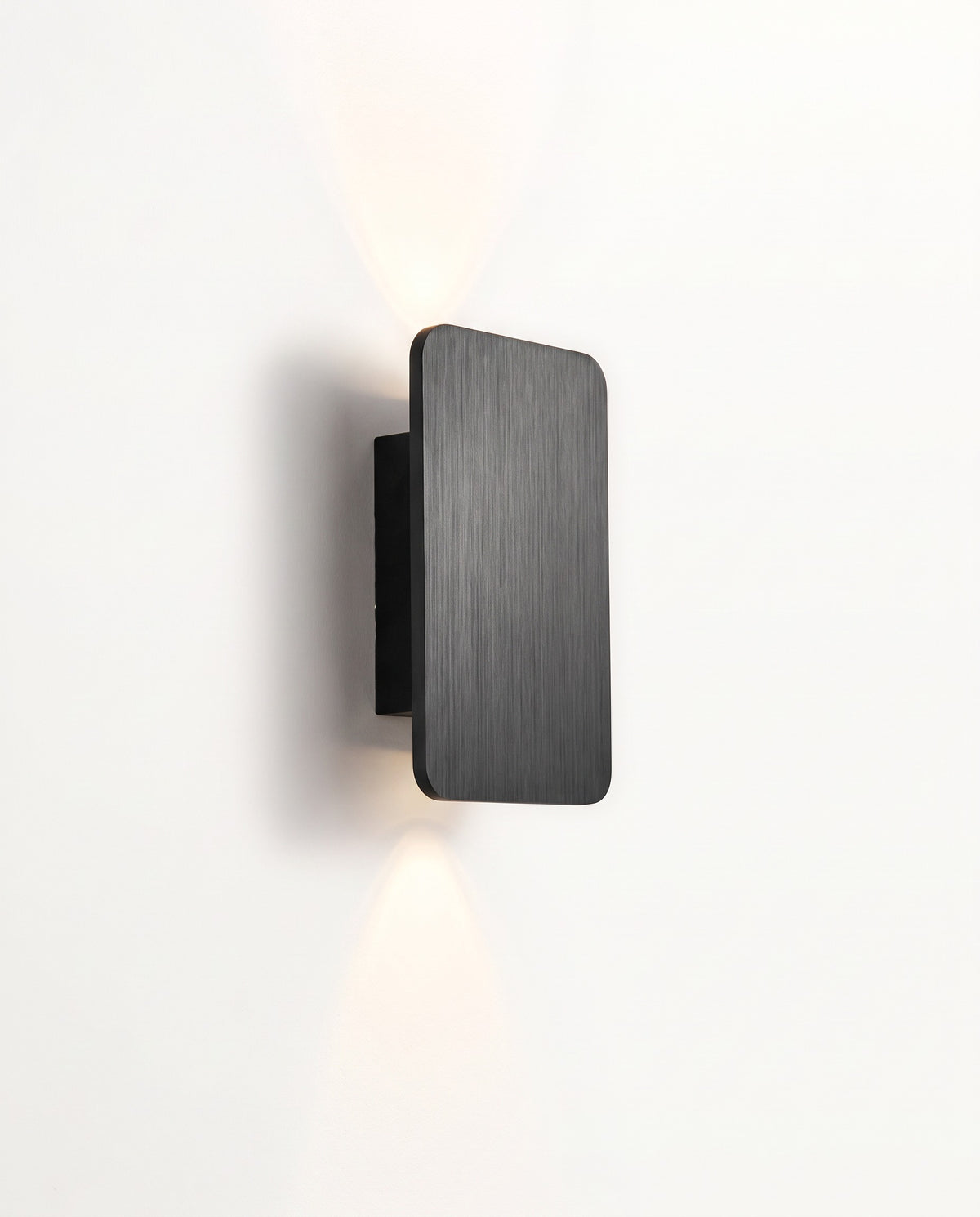 The Folio Wall Light in Jet, a brushed metal plate throwing light up and down the wall