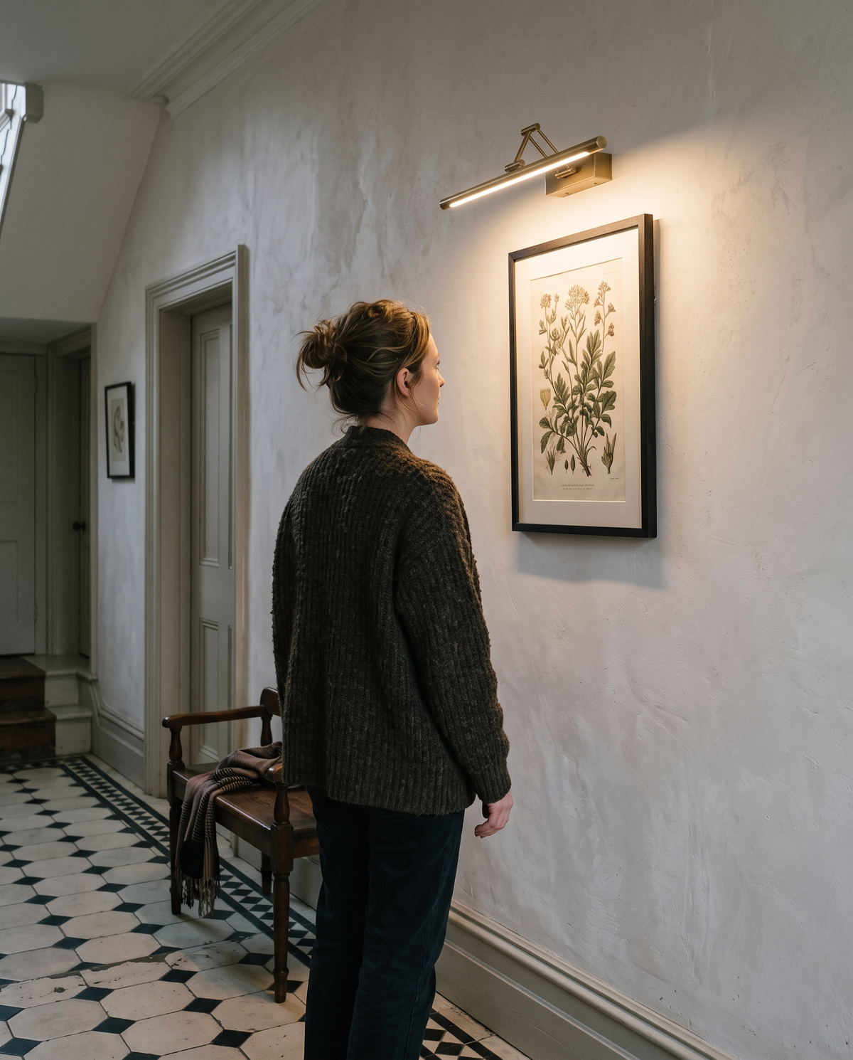 A woman looking at a botanical print lit by The Gallery in a Victorian hallway