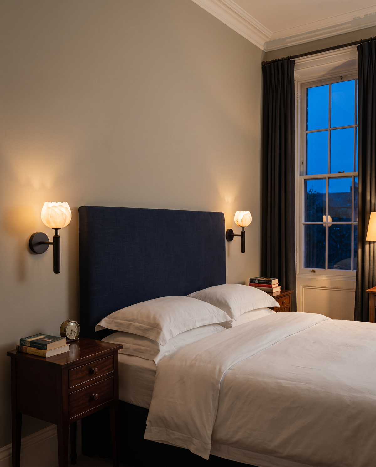 A pair of Gaslight wall lights in Jet either side of a navy headboard