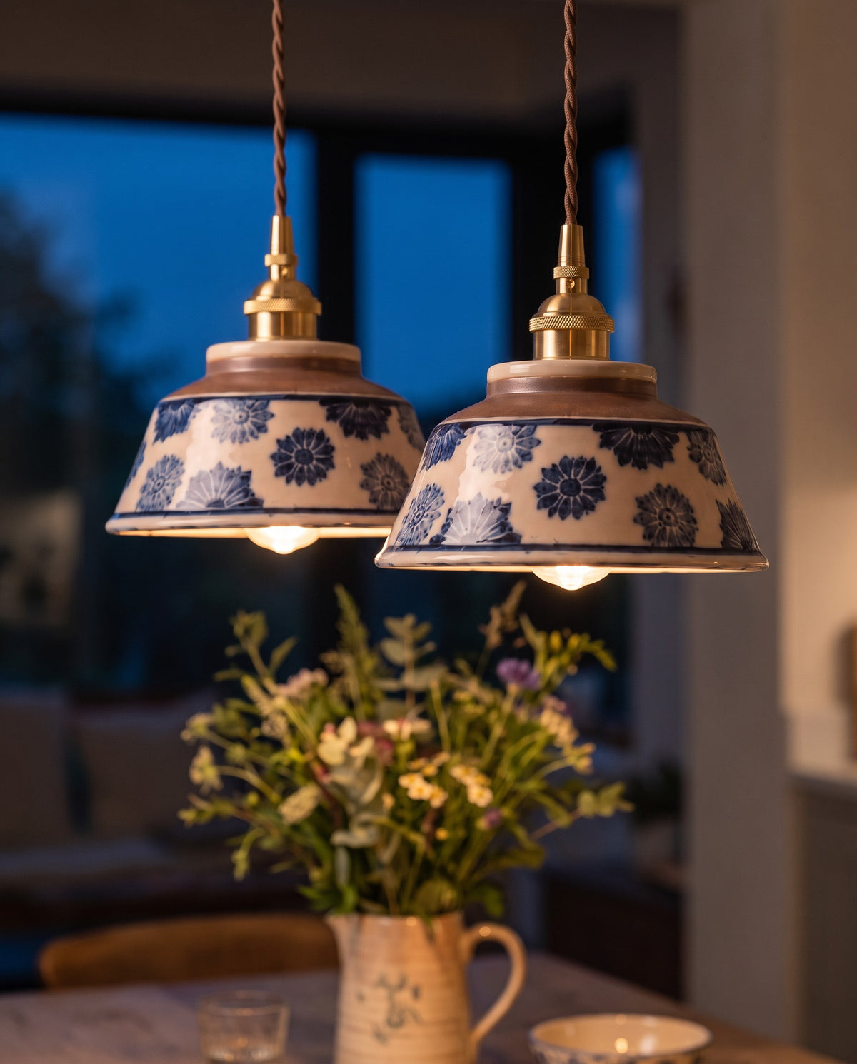 A pair of Kiln hand-painted ceramic pendants lit over a kitchen table