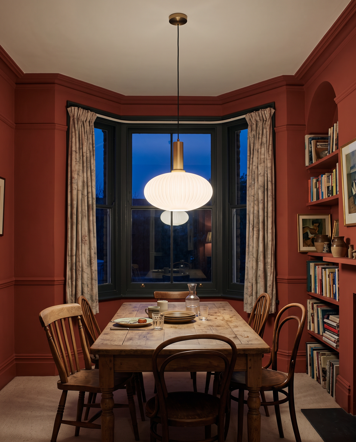 An opal Larder drum over an oak table in a terracotta dining room