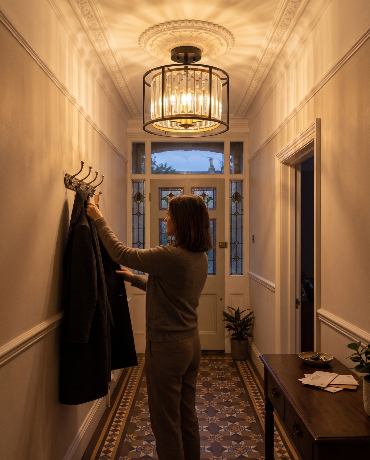 A woman hanging her coat in the hallway under The Lustre