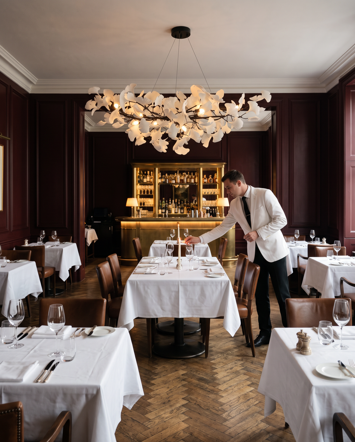 A maître d' lighting candles under The Maidenhair in Jet in a London restaurant