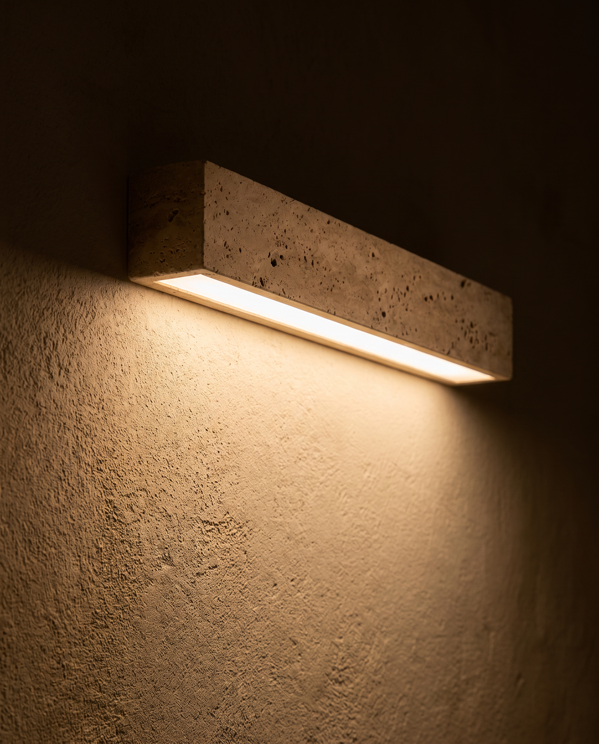 The travertine Monolith wall light washing warm light down a plaster wall